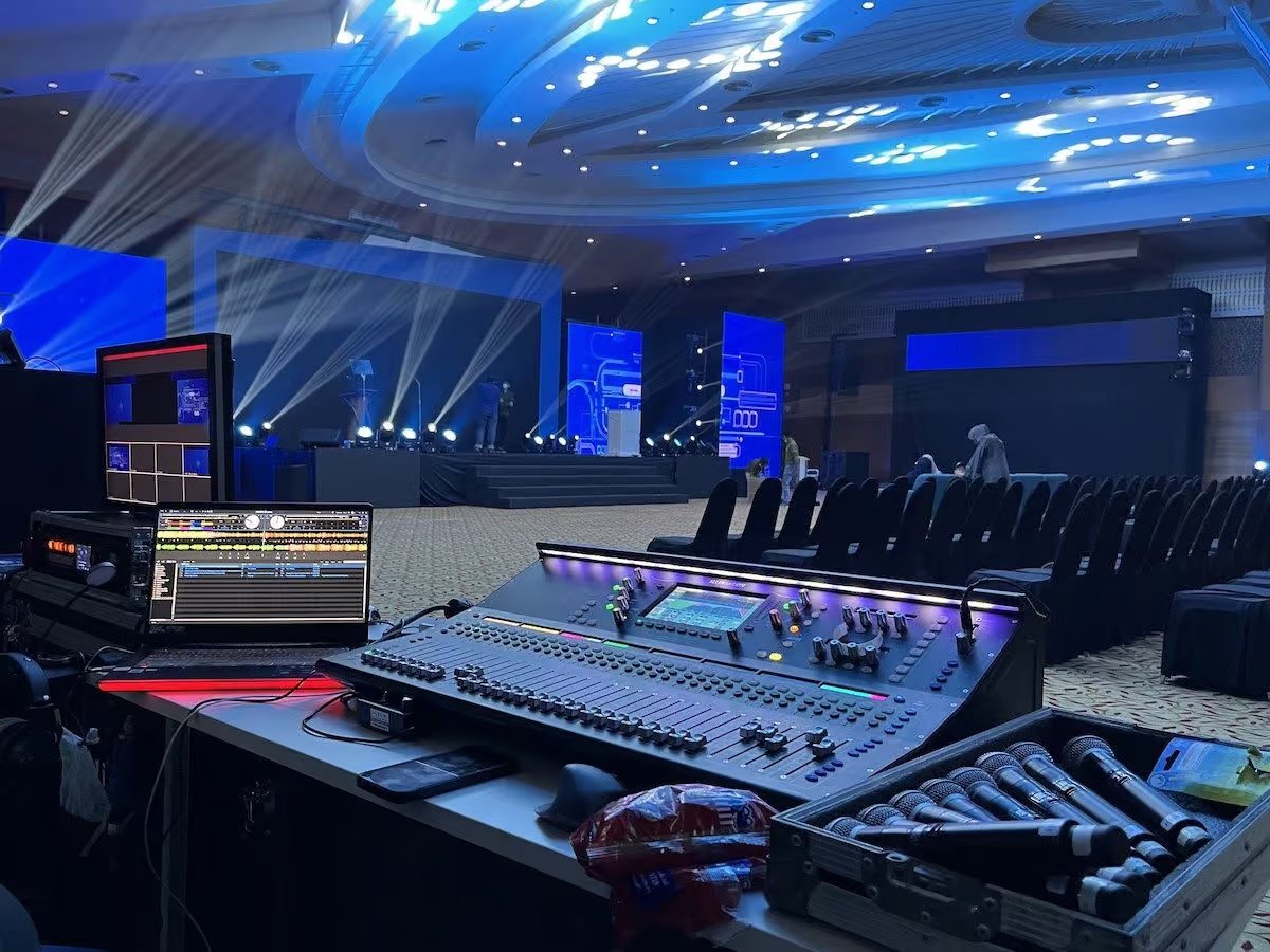 Stage lighting rig casting coloured beams over a live event